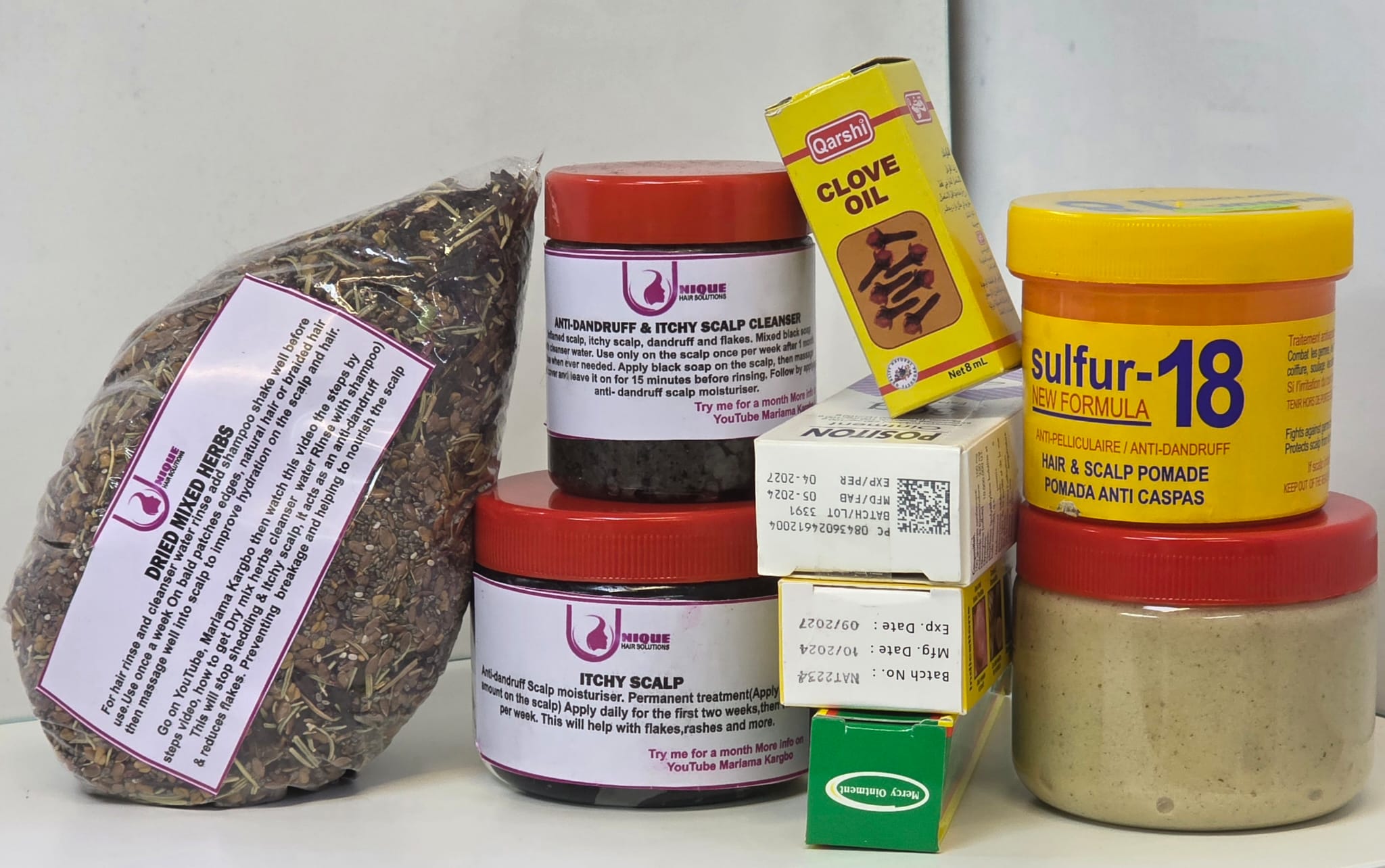 Collection of hair care products including jars and a bag of dried mixed herbs.